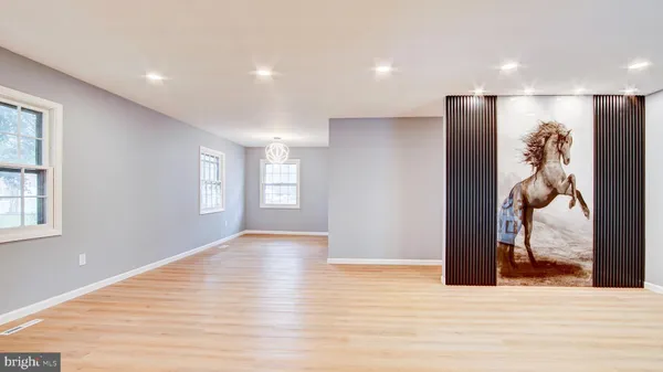 a view of an empty room with wooden floor and window