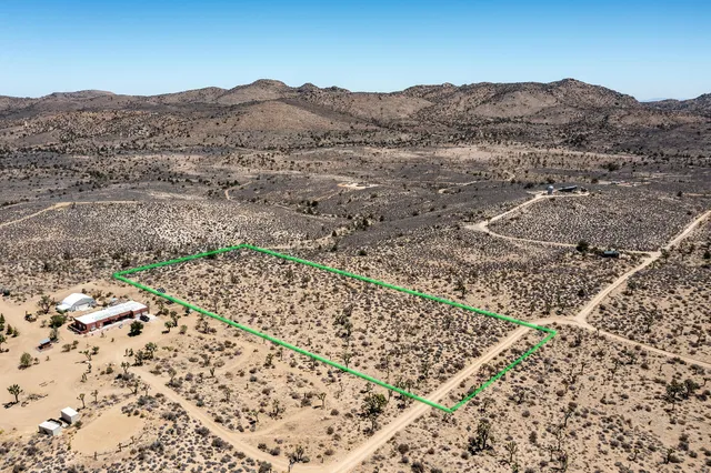 a view of a dry field with mountains in the background