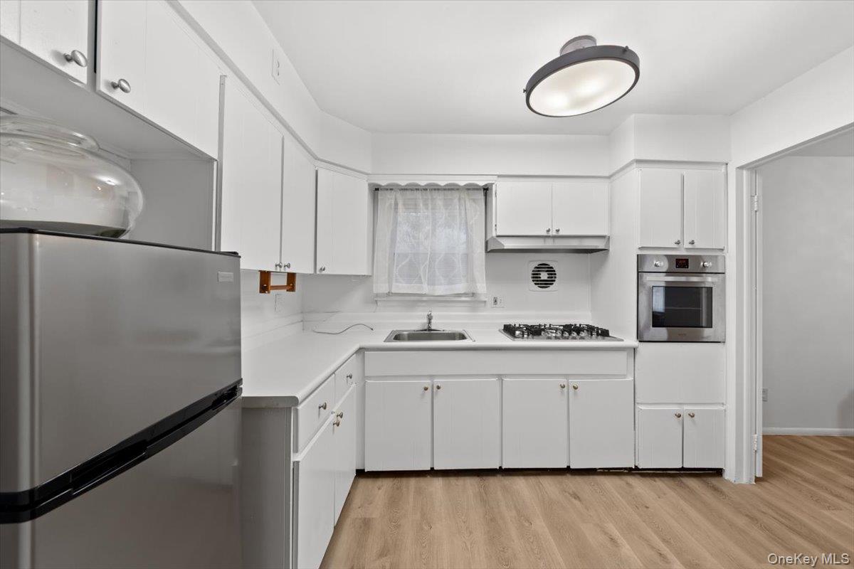 5824 Fieldston Road Bronx, NY 10471 - Photo 10 of 27 a kitchen with kitchen island white cabinets and refrigerator