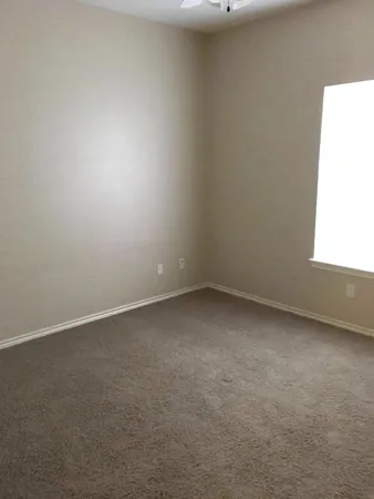 an empty room with a chandelier fan and windows