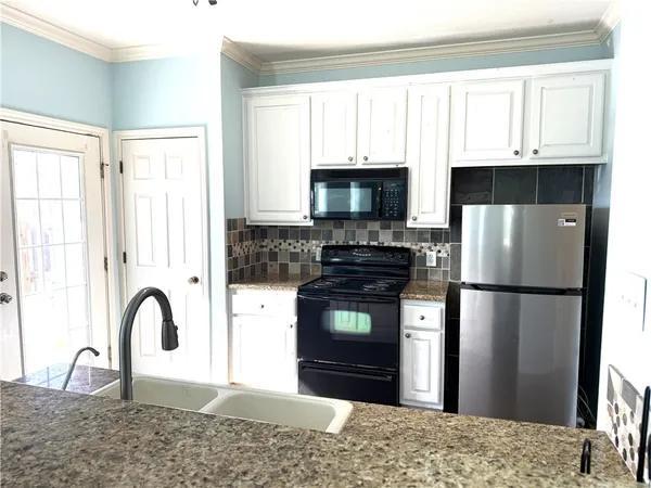 a kitchen with granite countertop a refrigerator stove and microwave