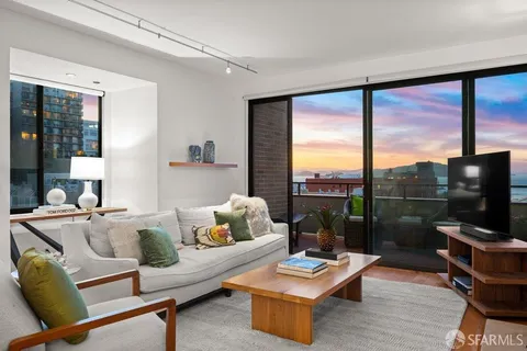 a living room with furniture a large window and wooden floor