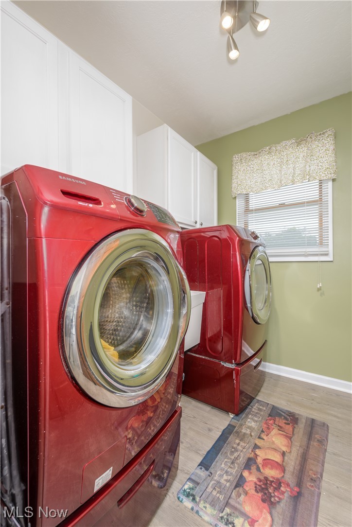 1435 Industry Road Atwater, OH 44201 - Photo 16 of 48 First floor laundry room with independent washer and dryer, cabinets, and LVT floors, just off of the kitchen