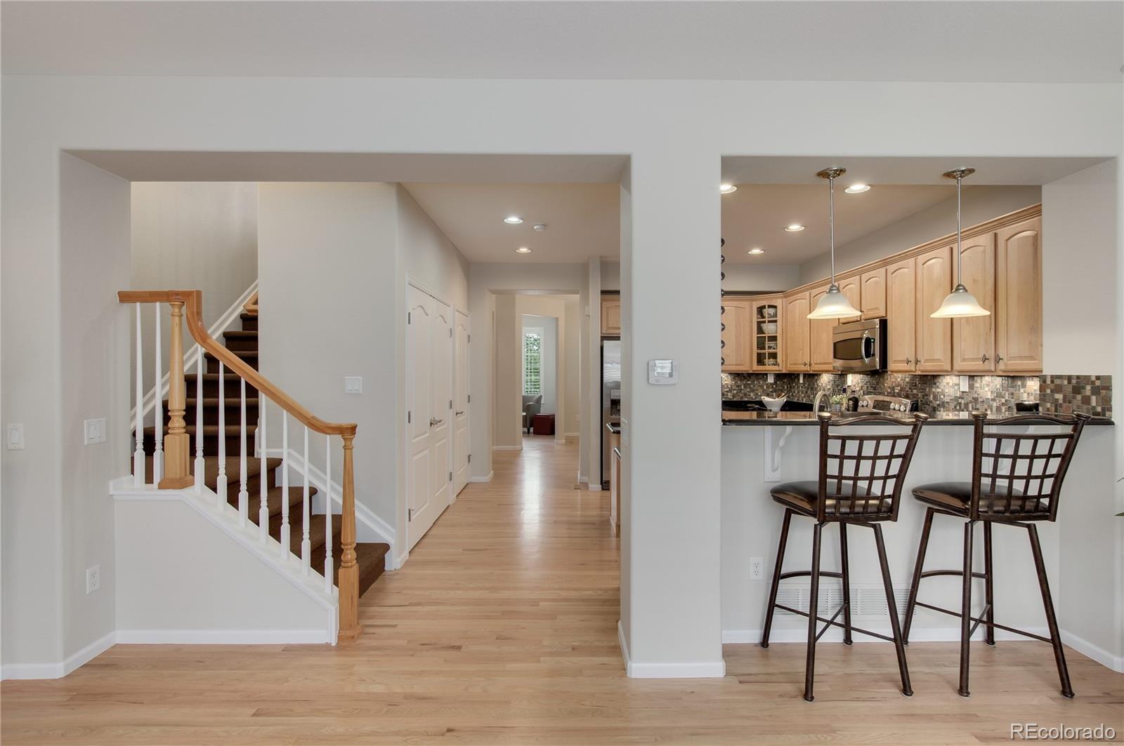 624 Green Ash Street, Unit G Highlands Ranch, CO 80129 - Photo 8 of 40 a view of a hallway with wooden floor chairs and a kitchen view