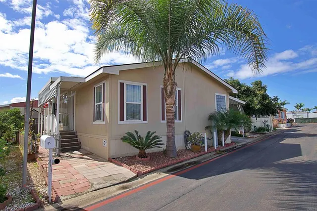 a palm tree sitting in front of a house with a patio