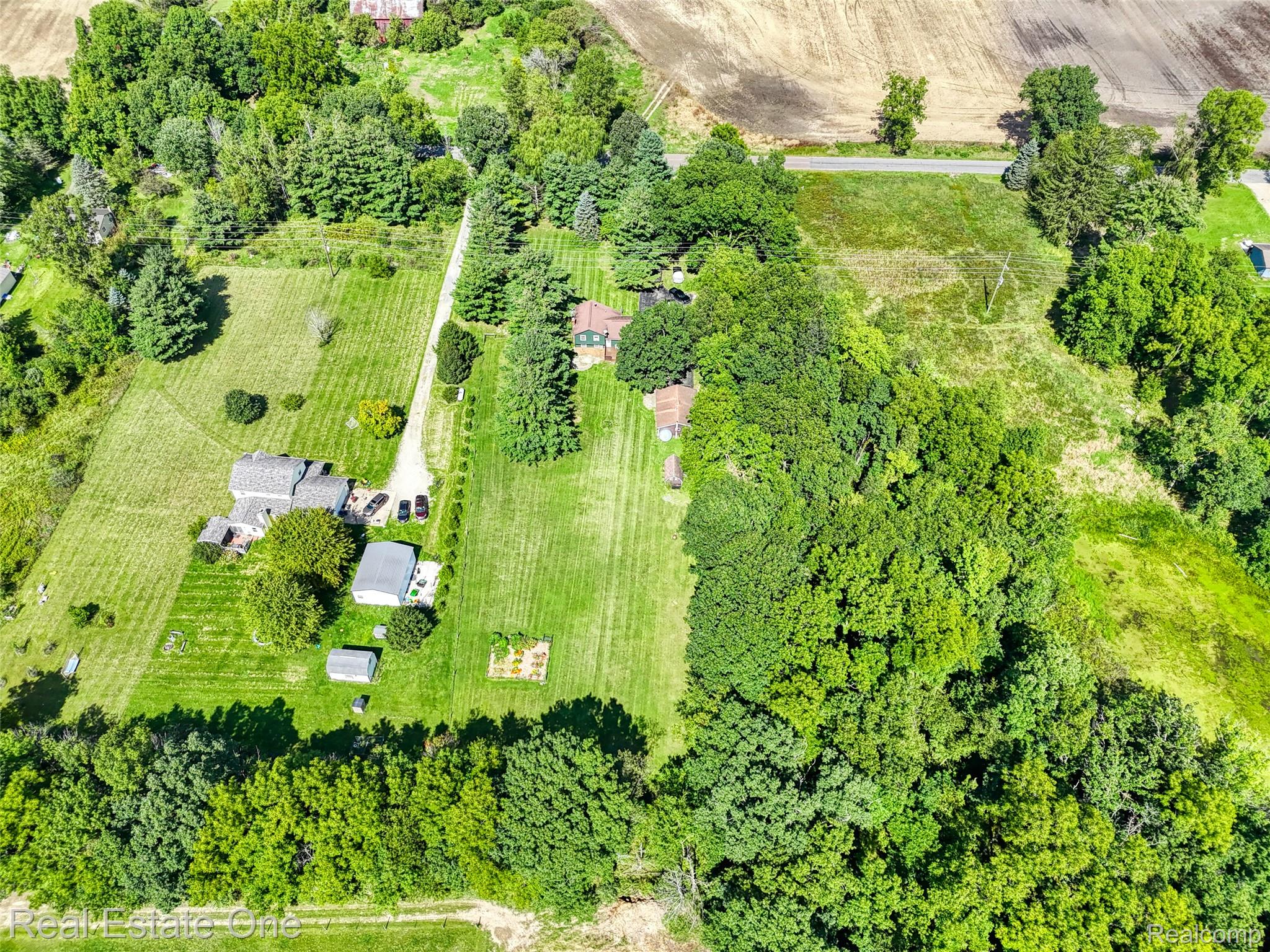5130 Iosco Road Webberville, MI 48892 - Photo 35 of 39 Expansive property featuring multiple structures, mature trees, a gravel driveway, and cultivated land