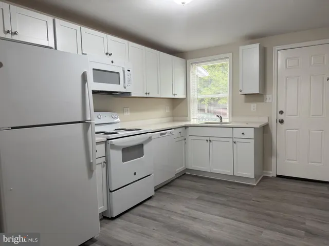 a kitchen with a white cabinets and wooden floor