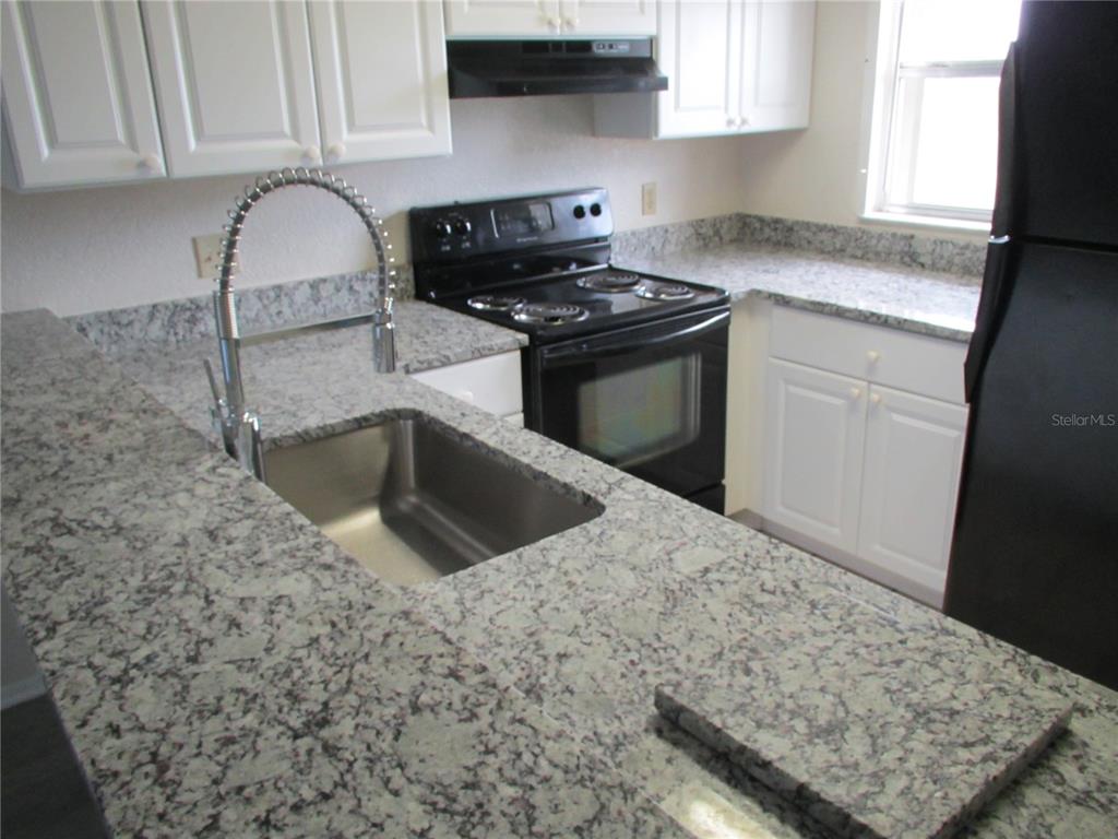 25100 Sandhill Boulevard, Unit 202 Punta Gorda, FL 33983 - Photo 10 of 12 a kitchen with granite countertop a sink a stove and cabinets