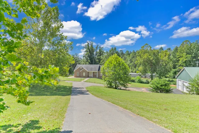 a front view of a house with a garden and trees