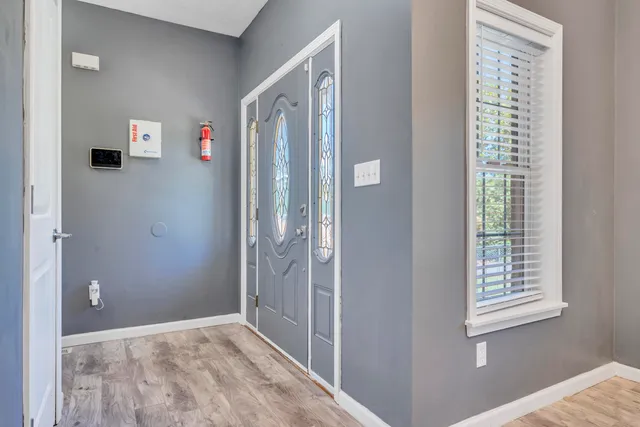a view of an empty room with window and wooden floor