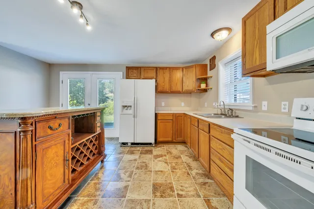 an empty room with wooden floor chandelier fan and windows