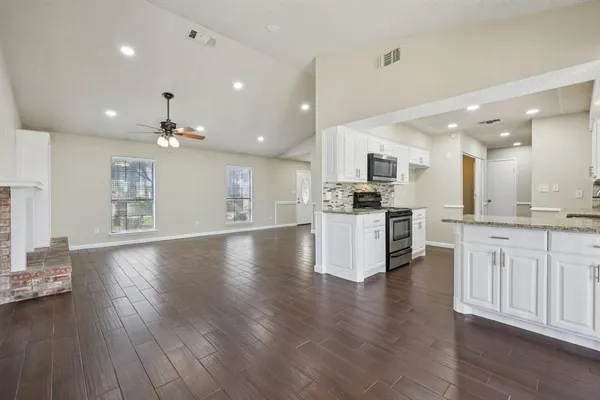 a kitchen with granite countertop a sink a counter top space stainless steel appliances and cabinets