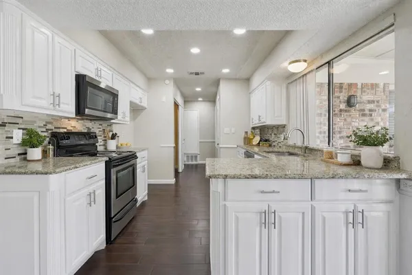 a kitchen with stainless steel appliances granite countertop a stove a sink and a refrigerator