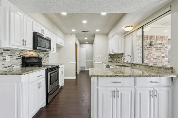 a kitchen with stainless steel appliances granite countertop a stove a sink and a microwave