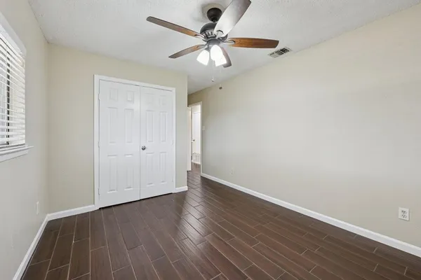 an empty room with wooden floor and ceiling fan
