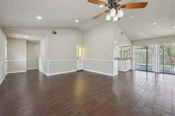 an empty room with wooden floor fan and windows