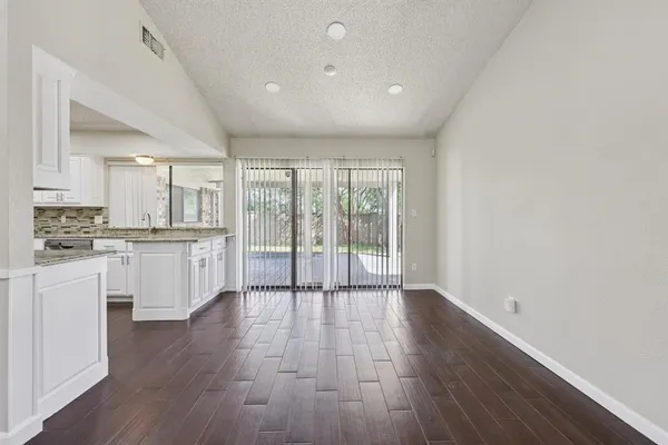 a large kitchen with white cabinets and wooden floor