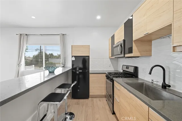 a kitchen with stainless steel appliances a sink dishwasher a refrigerator and a stove with wooden floor