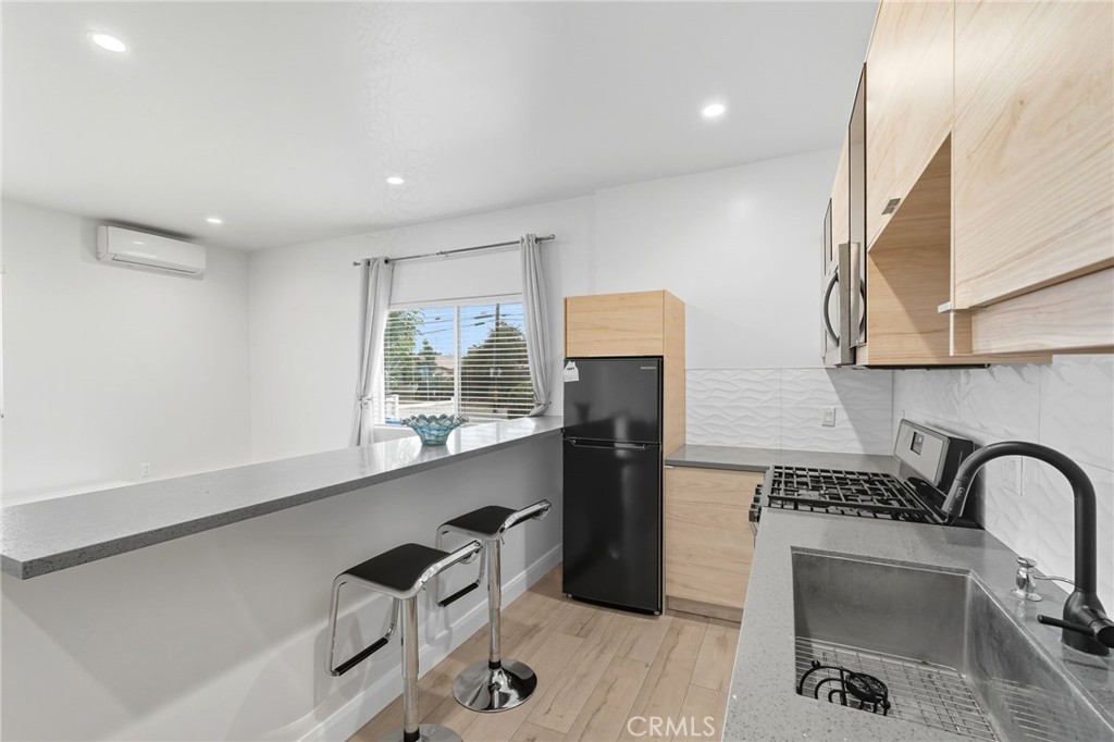 11642 Gothic Avenue Granada Hills, CA 91344 - Photo 15 of 27 a kitchen with stainless steel appliances a sink dishwasher a refrigerator and a stove with wooden floor