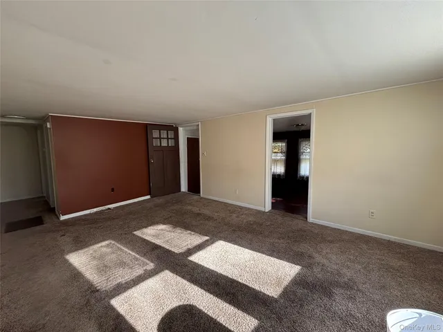 a view of an empty room with window and stairs