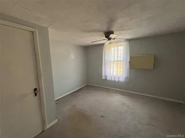 an empty room with a window and a ceiling fan