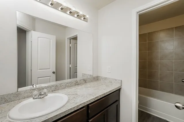 a bathroom with a granite countertop sink a mirror and a bathtub