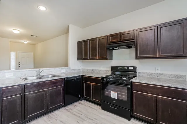 a kitchen with stainless steel appliances granite countertop wooden cabinets a stove a sink and dishwasher