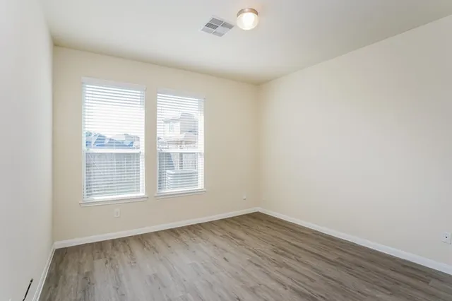 an empty room with wooden floor and windows