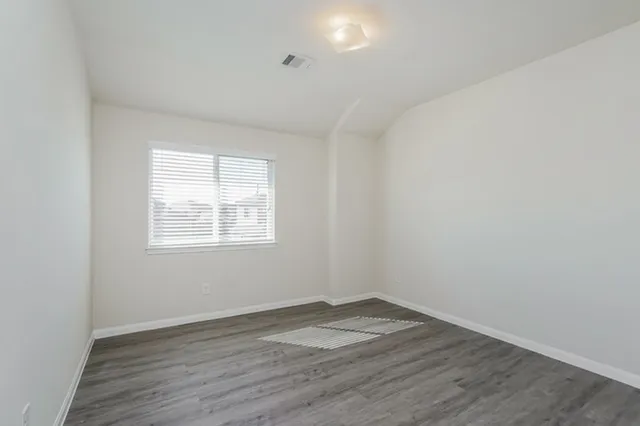 an empty room with wooden floor and window