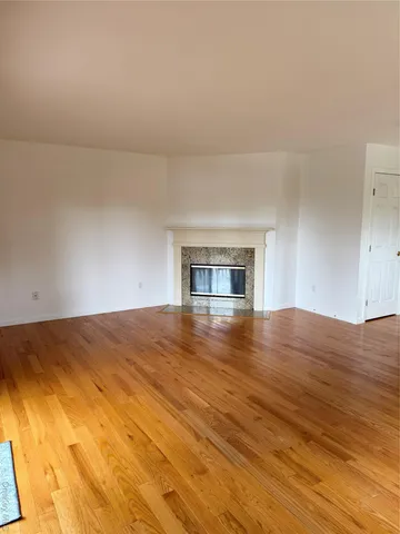 a view of empty room with wooden floor and fireplace