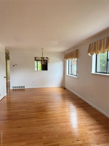 a view of an empty room with window and wooden floor