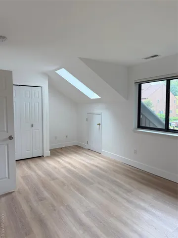 a view of an empty room with wooden floor and window
