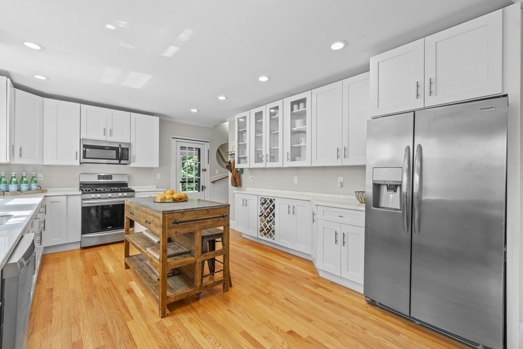 26 Cedar Street, Unit 2 Marblehead, MA 01945 - Photo 17 of 37 a kitchen with stainless steel appliances granite countertop a refrigerator a stove top oven a sink dishwasher and white cabinets with wooden floor