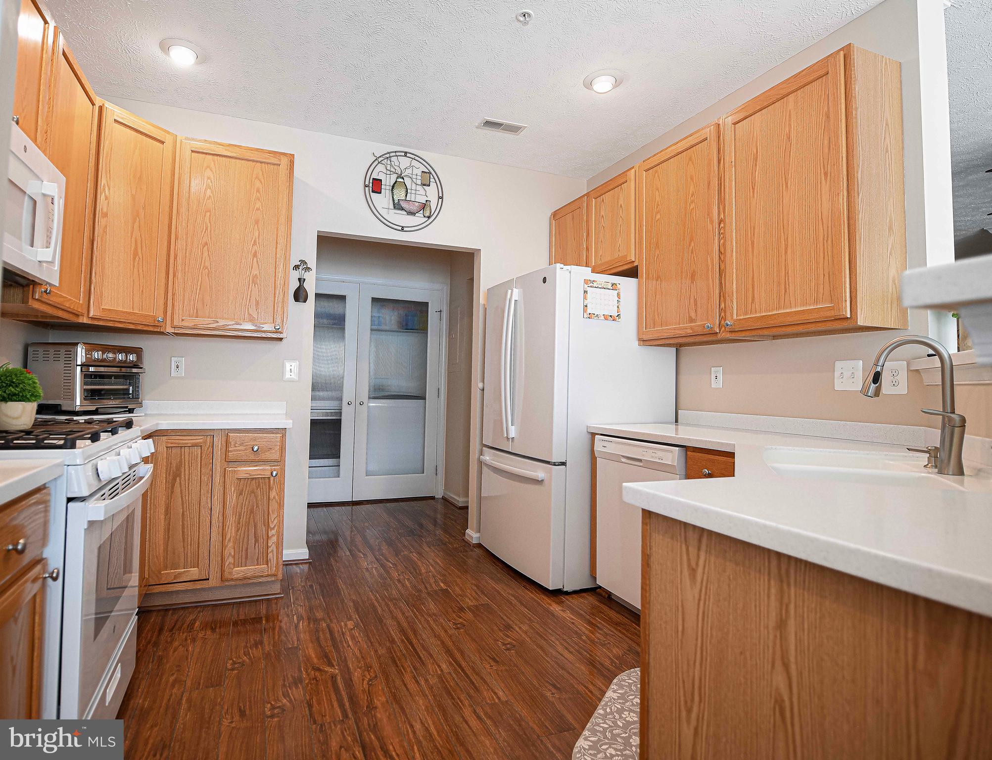 9506 Amberleigh Lane, Unit 9506A Perry Hall, MD 21128 - Photo 23 of 33 a kitchen with stainless steel appliances granite countertop a refrigerator a sink dishwasher and wooden cabinets with wooden floor