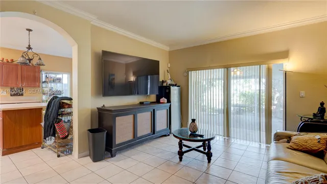 a living room with furniture a flat screen tv and a refrigerator