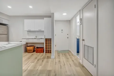 a room with stainless steel appliances wooden floor and a view of kitchen