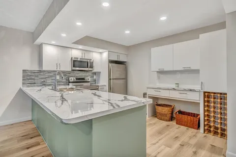 a kitchen with kitchen island stainless steel appliances a sink stove and oven