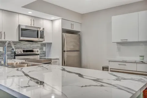 a kitchen with stainless steel appliances granite countertop a refrigerator and a stove top oven