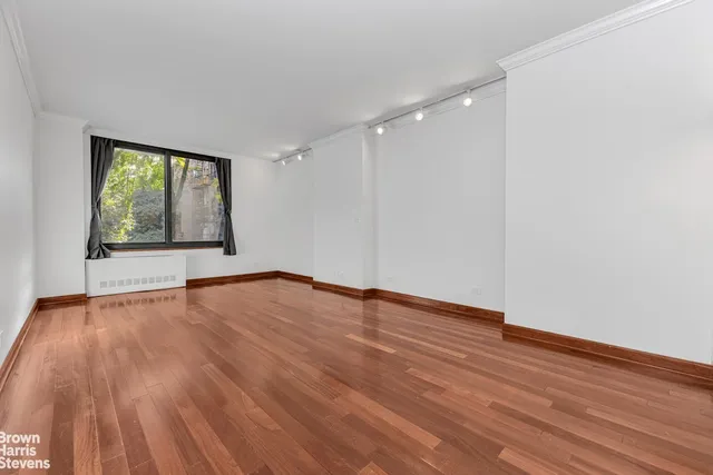 a view of an empty room with wooden floor and a window