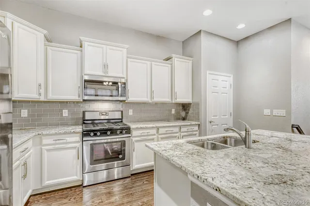 a kitchen with granite countertop a sink a stove and cabinets