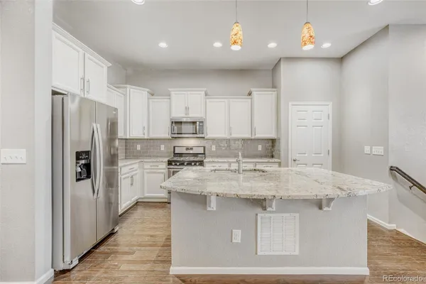 a kitchen with kitchen island a sink stainless steel appliances and white cabinets