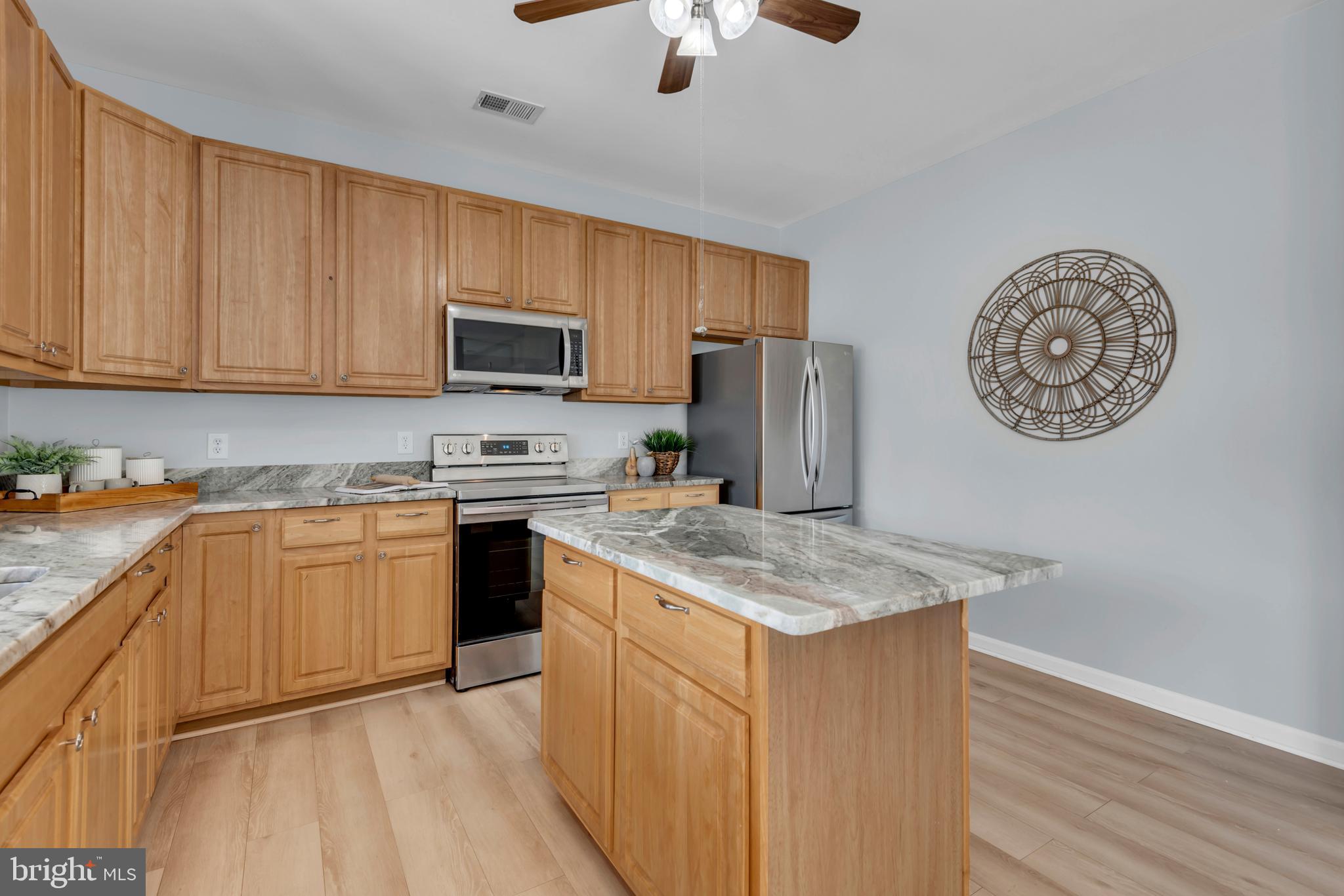 1104 Ruddy Duck Court Denton, MD 21629 - Photo 19 of 50 a kitchen with stainless steel appliances granite countertop a stove top oven a refrigerator a sink and dishwasher with wooden floor
