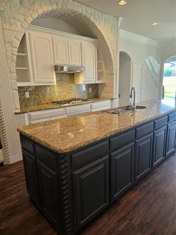 a kitchen with granite countertop a sink a stove and cabinets