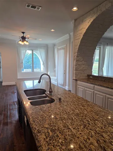 a kitchen with granite countertop a stove a sink and a wooden floors