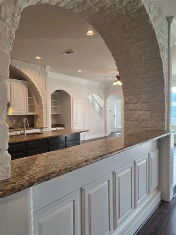 a large white kitchen with granite countertop a sink and white cabinets