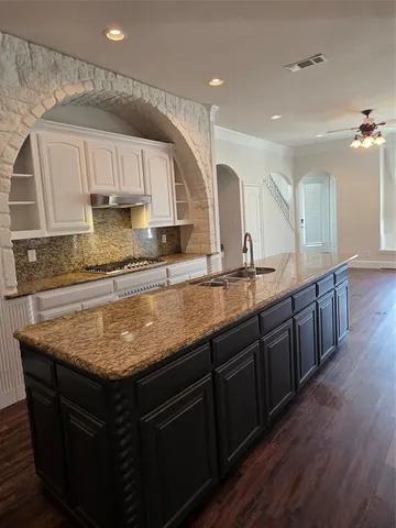 a kitchen with granite countertop a sink a counter top space and cabinets