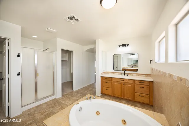 a spacious bathroom with a tub sink and mirror