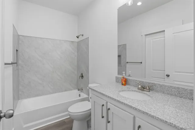 a bathroom with a granite countertop sink a toilet and shower