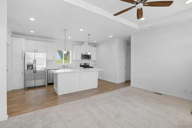 a large white kitchen with a refrigerator a stove top oven a sink and dishwasher