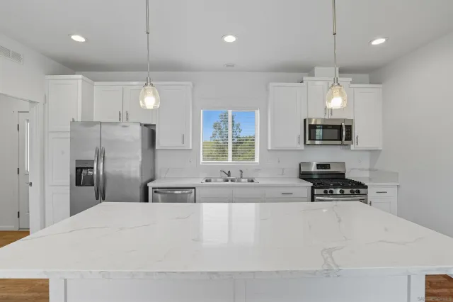 a large white kitchen with a refrigerator a stove a sink and a window